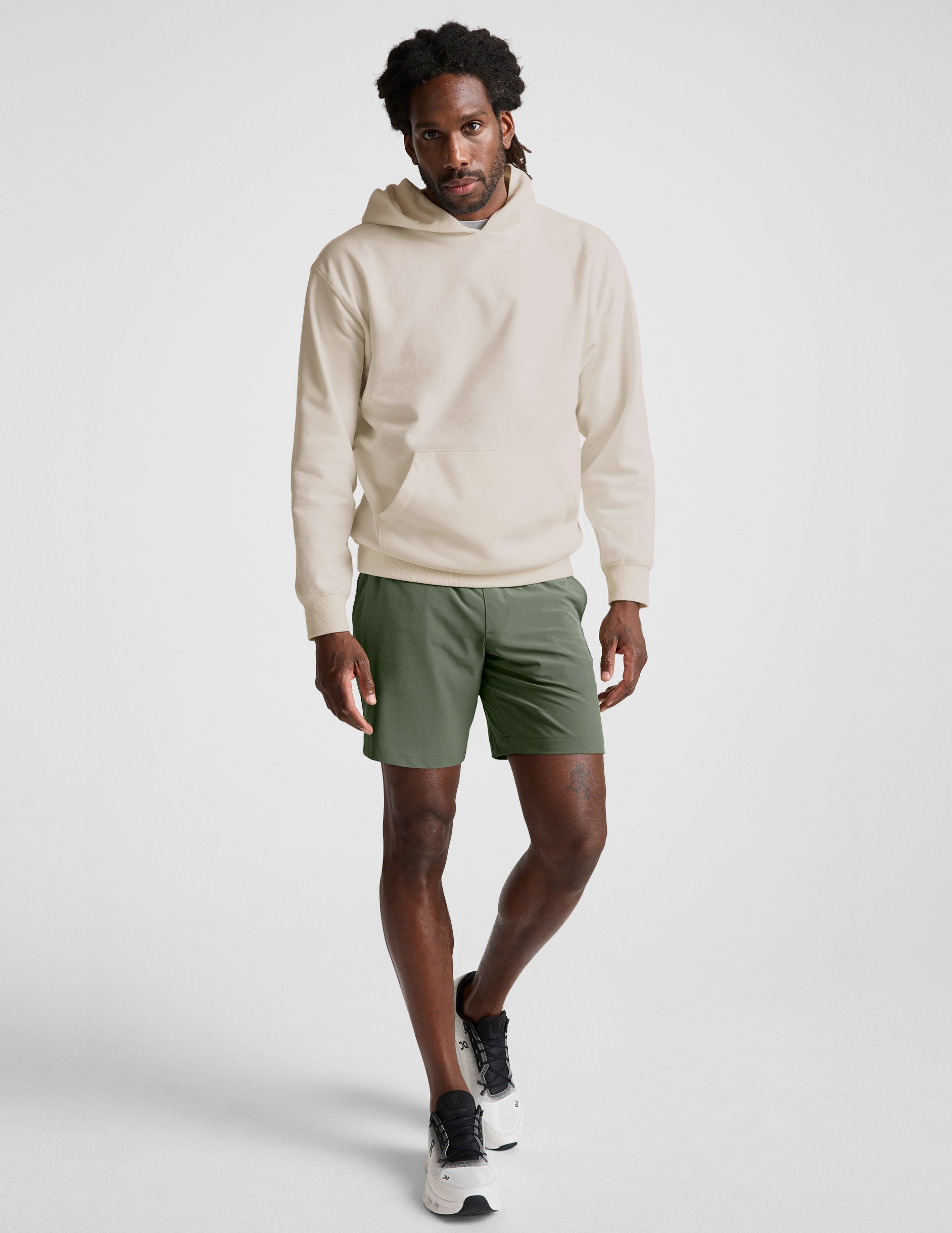 man wearing a white hoodie and green shorts on a white background.