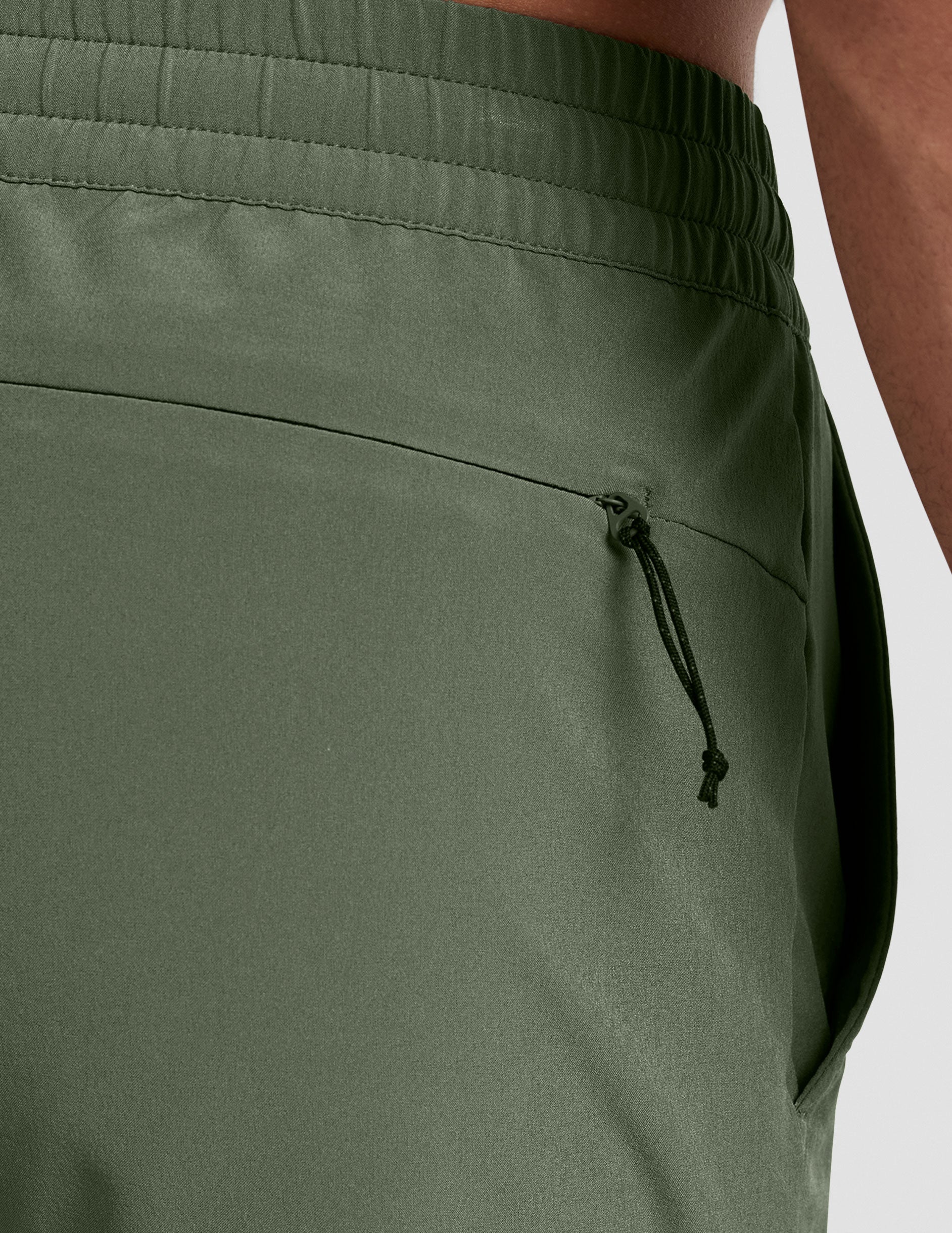 man wearing a gray t-shirt and green shorts on a plain background.