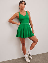 green mini dress in our stretch woven fabric with stitch down front pleats, a scoop front neckline​, open back detail​, bodice in performance stretch fabric​, and skirt side vents for easy pocket access​. 