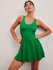 green mini dress in our stretch woven fabric with stitch down front pleats, a scoop front neckline​, open back detail​, bodice in performance stretch fabric​, and skirt side vents for easy pocket access​. 