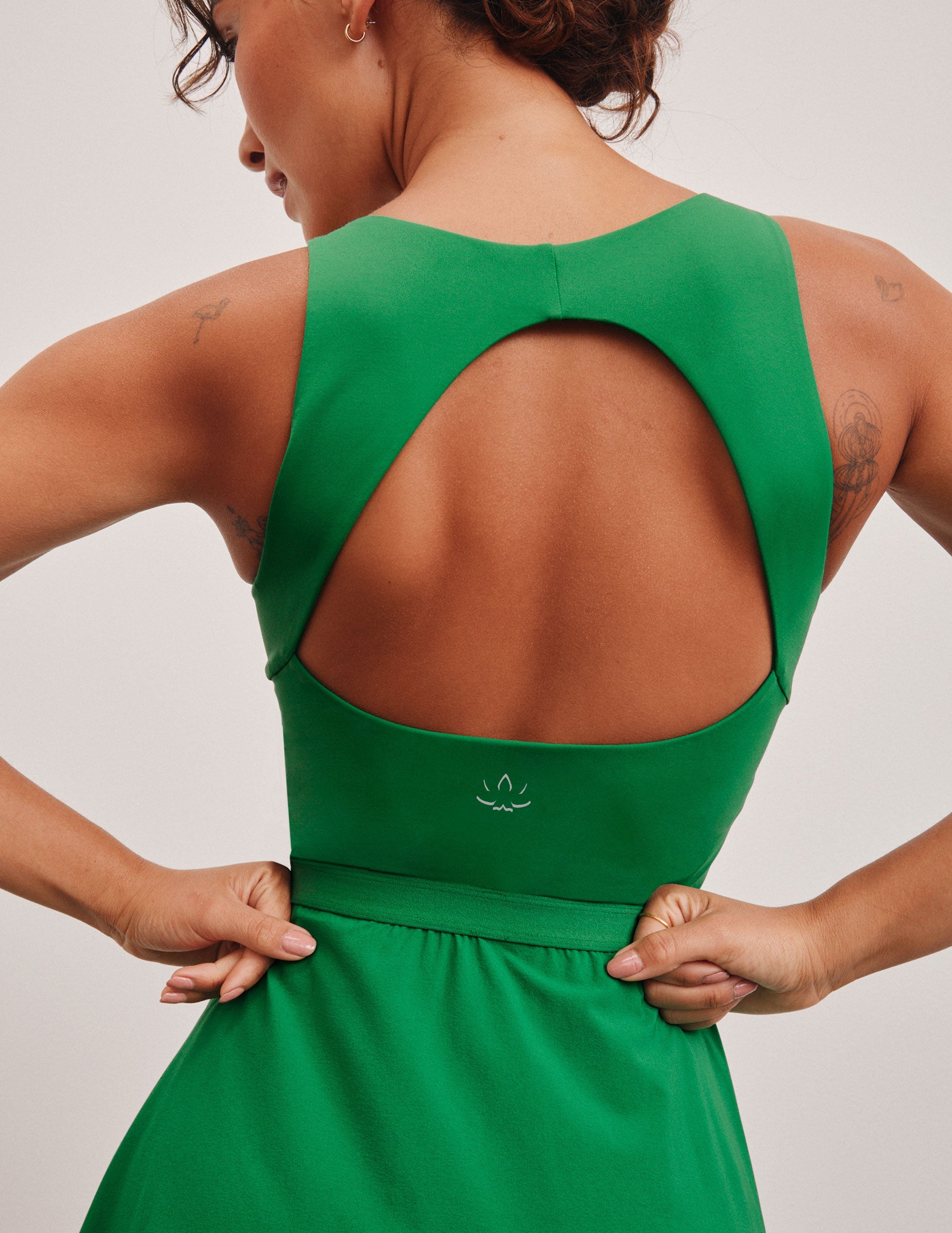 green mini dress in our stretch woven fabric with stitch down front pleats, a scoop front neckline​, open back detail​, bodice in performance stretch fabric​, and skirt side vents for easy pocket access​. 