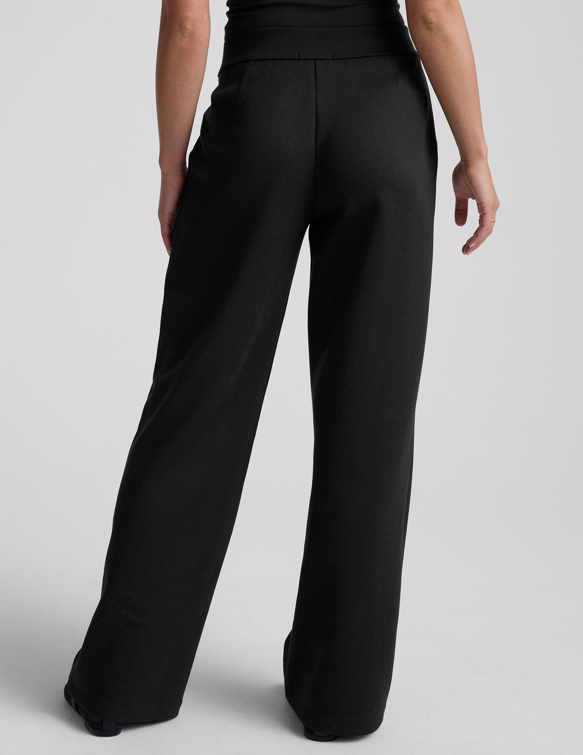 model is wearing a black sleeveless top and black spacer style pants with pockets against a plain background.