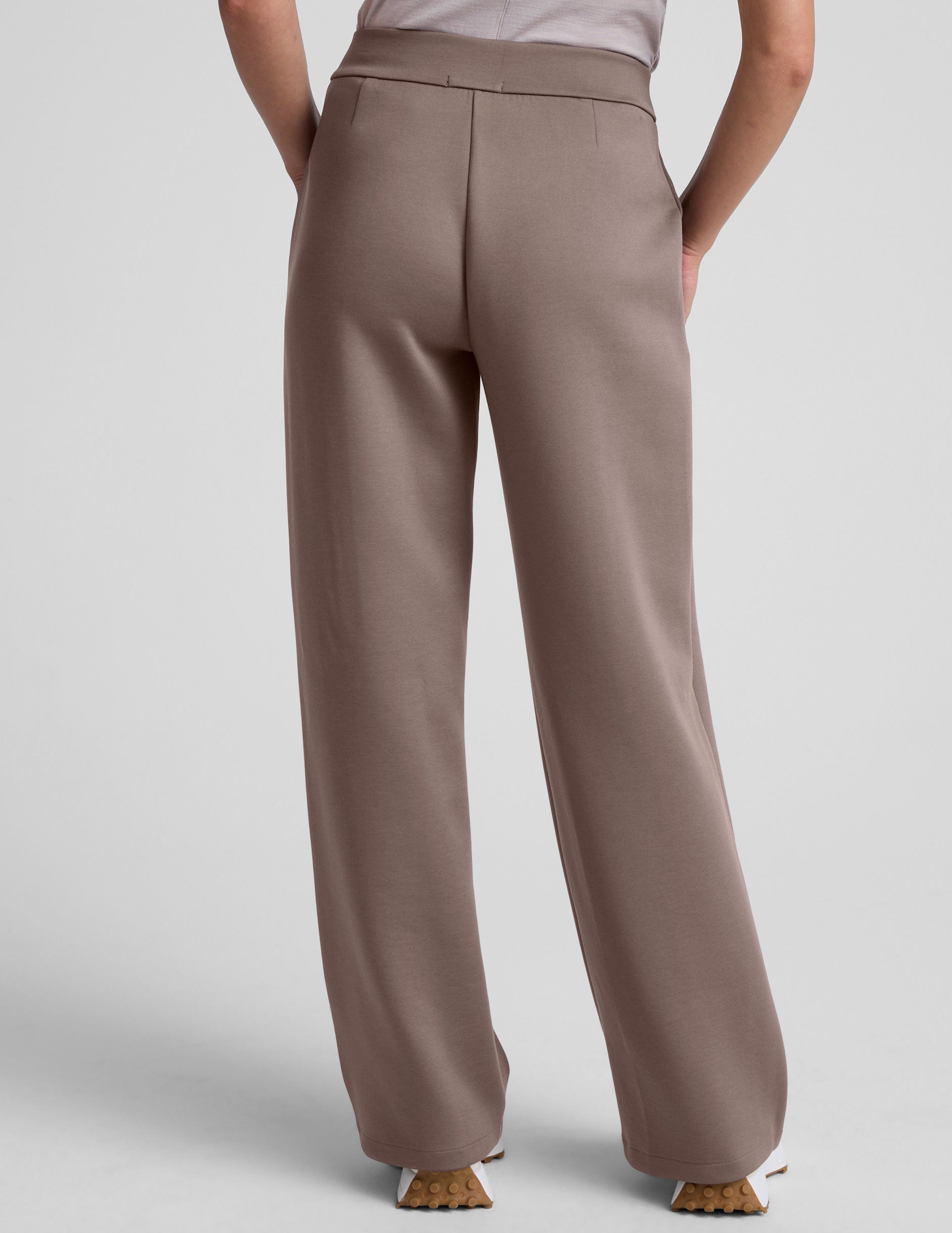 model is wearing brown spacer style pants with pockets against a plain background.