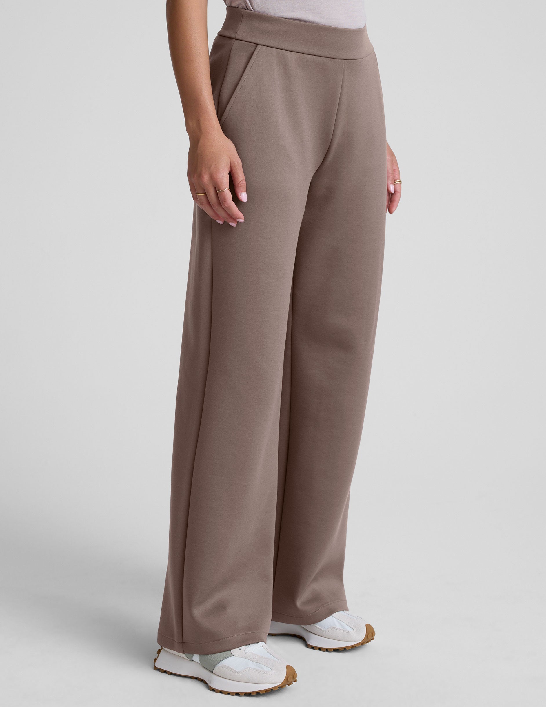 model is wearing brown spacer style pants with pockets against a plain background.