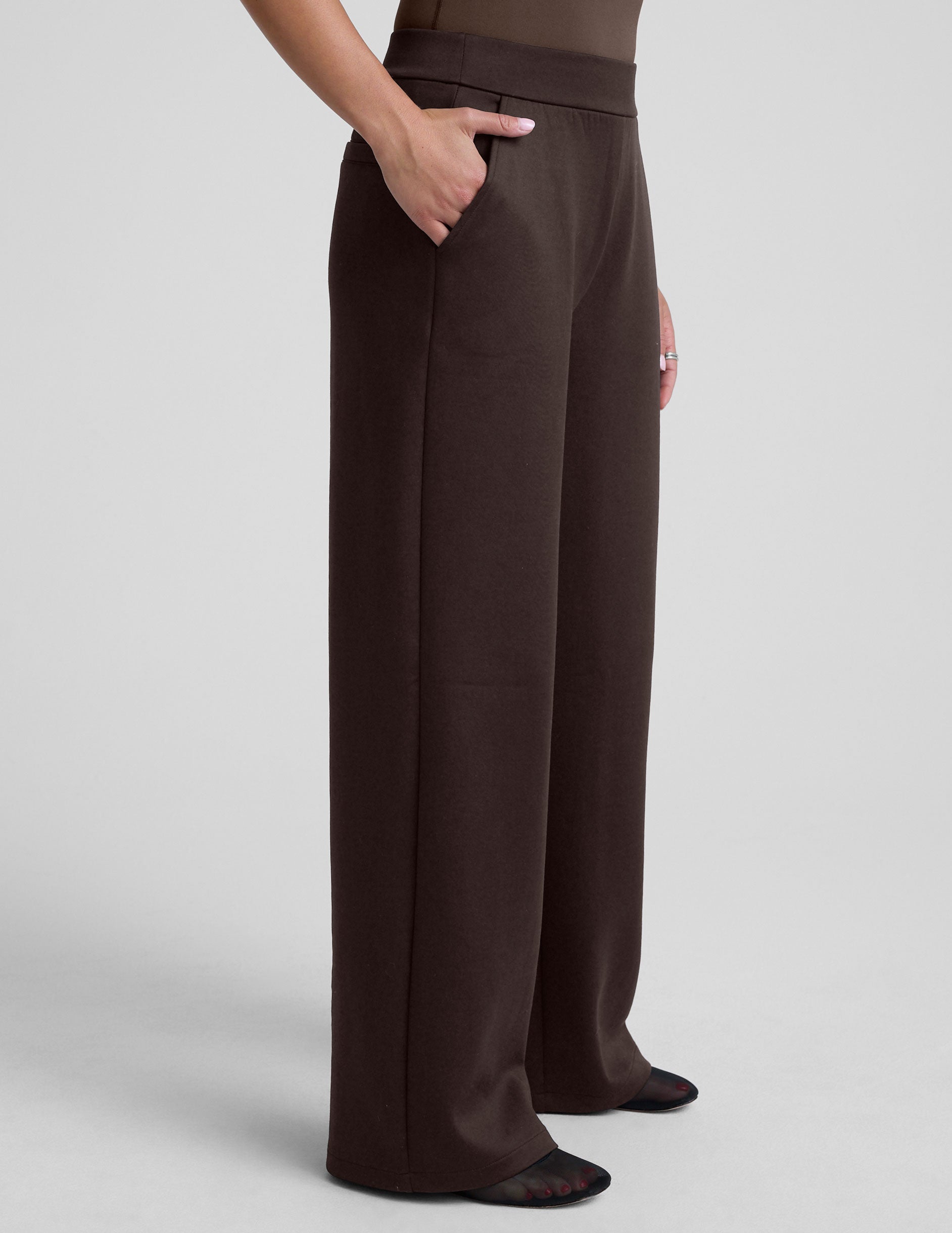 woman wearing brown wide-leg pants against a plain background.