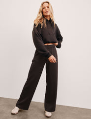 woman wearing a brown cropped hoodie with brown wide-leg pants against a plain background.