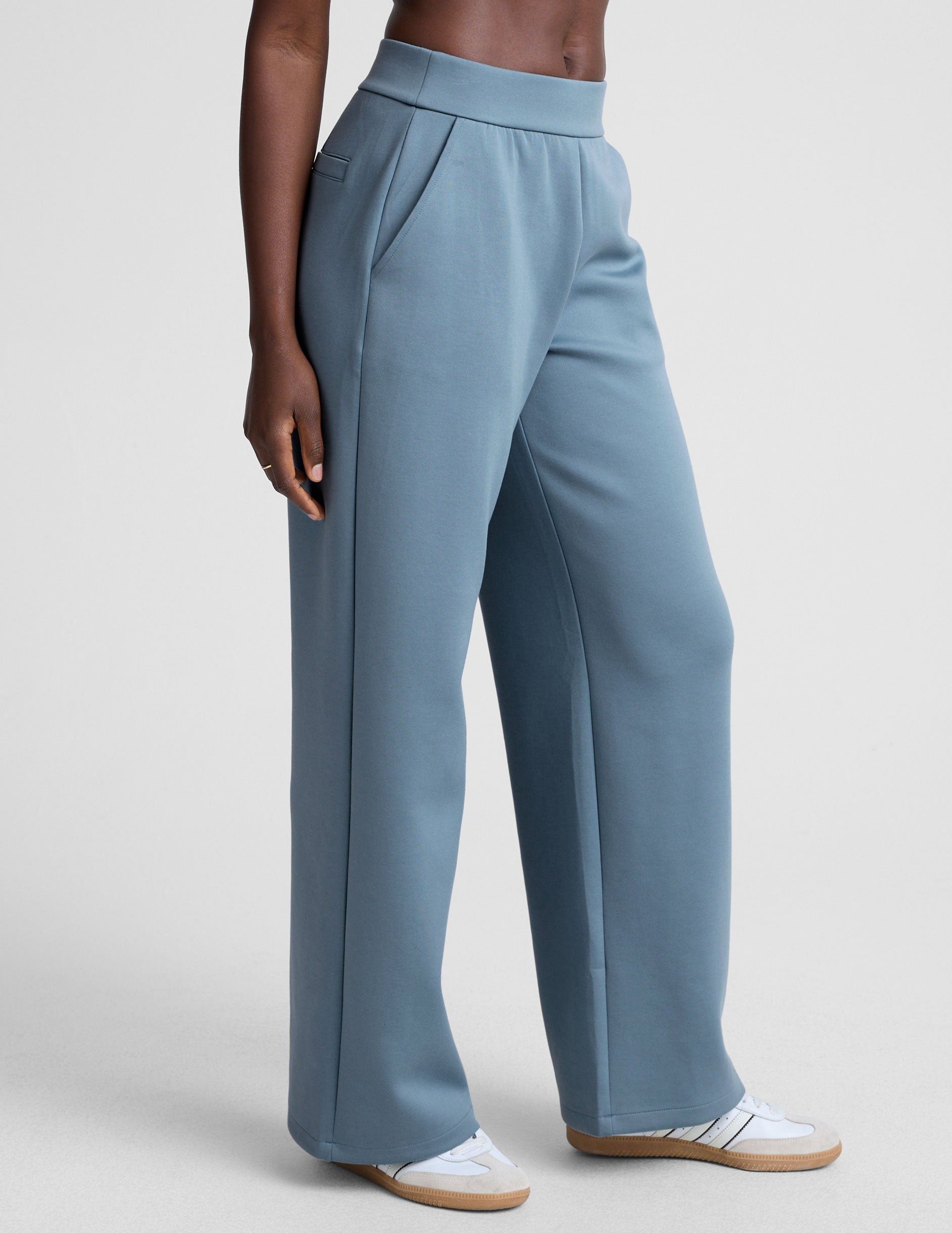 model is wearing blue spacer style pants with pockets against a plain background.