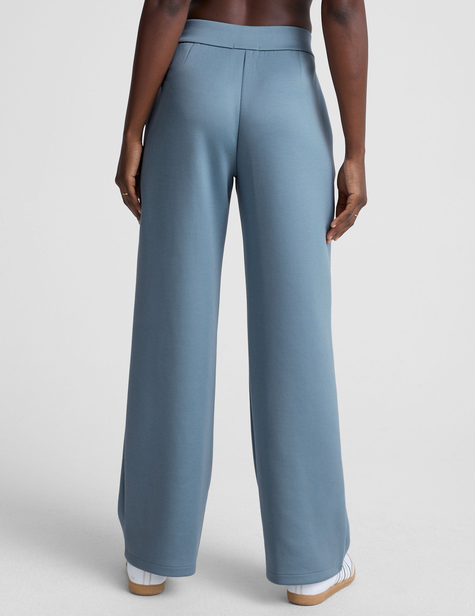 model is wearing blue spacer style pants with pockets against a plain background.