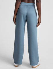 model is wearing blue spacer style pants with pockets against a plain background.