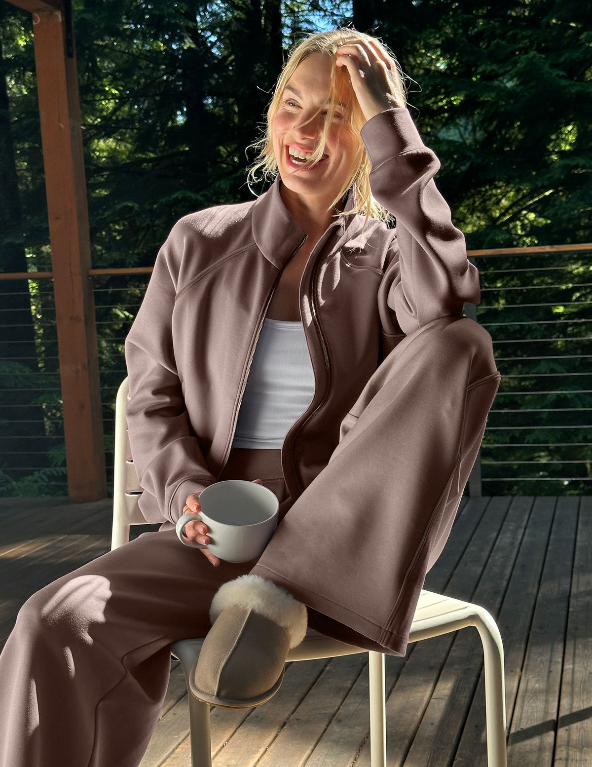 Woman wearing a brown zip-up jacket and pants sitting on a porch.