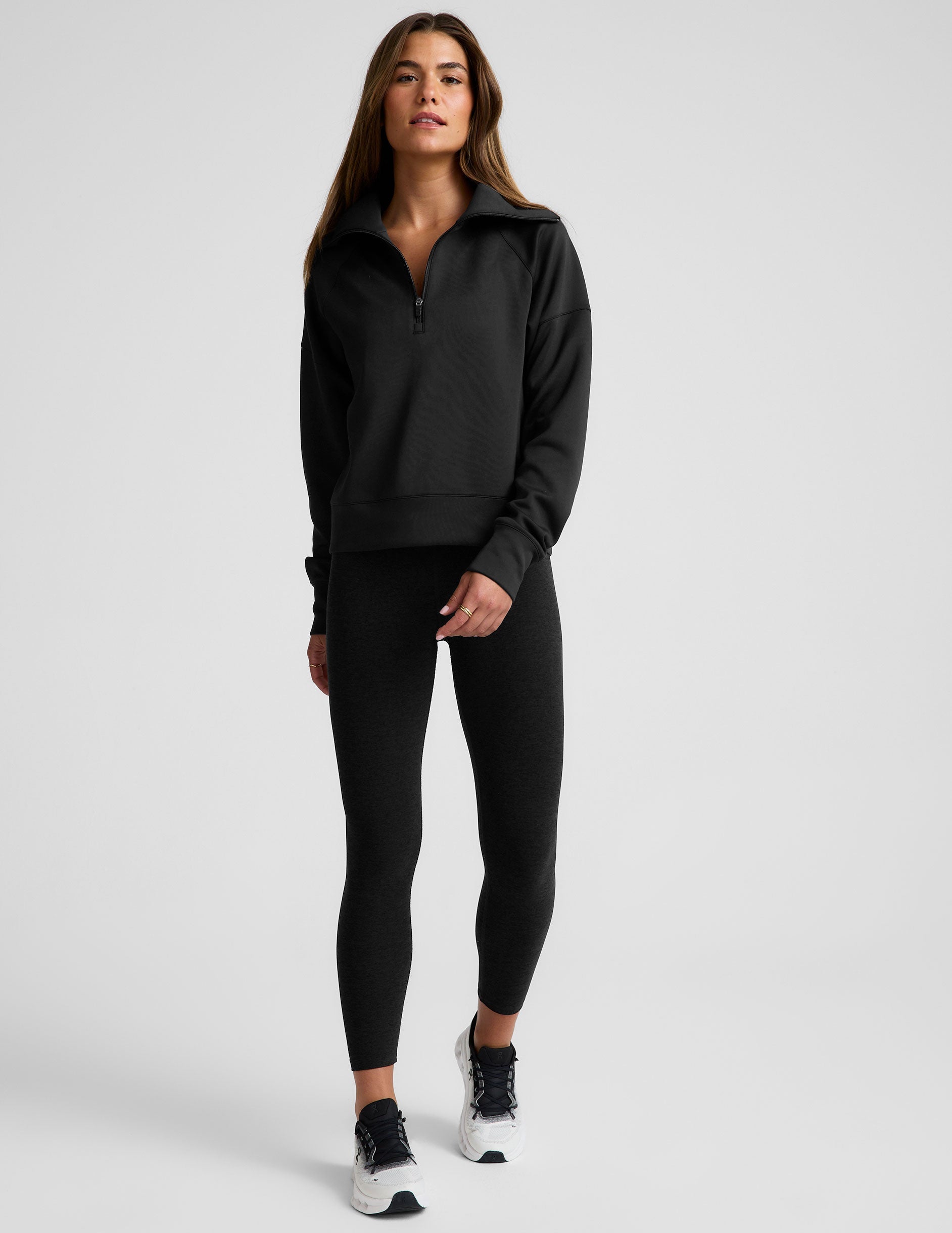 model wearing a black long length quarter zip pullover against a plain background.