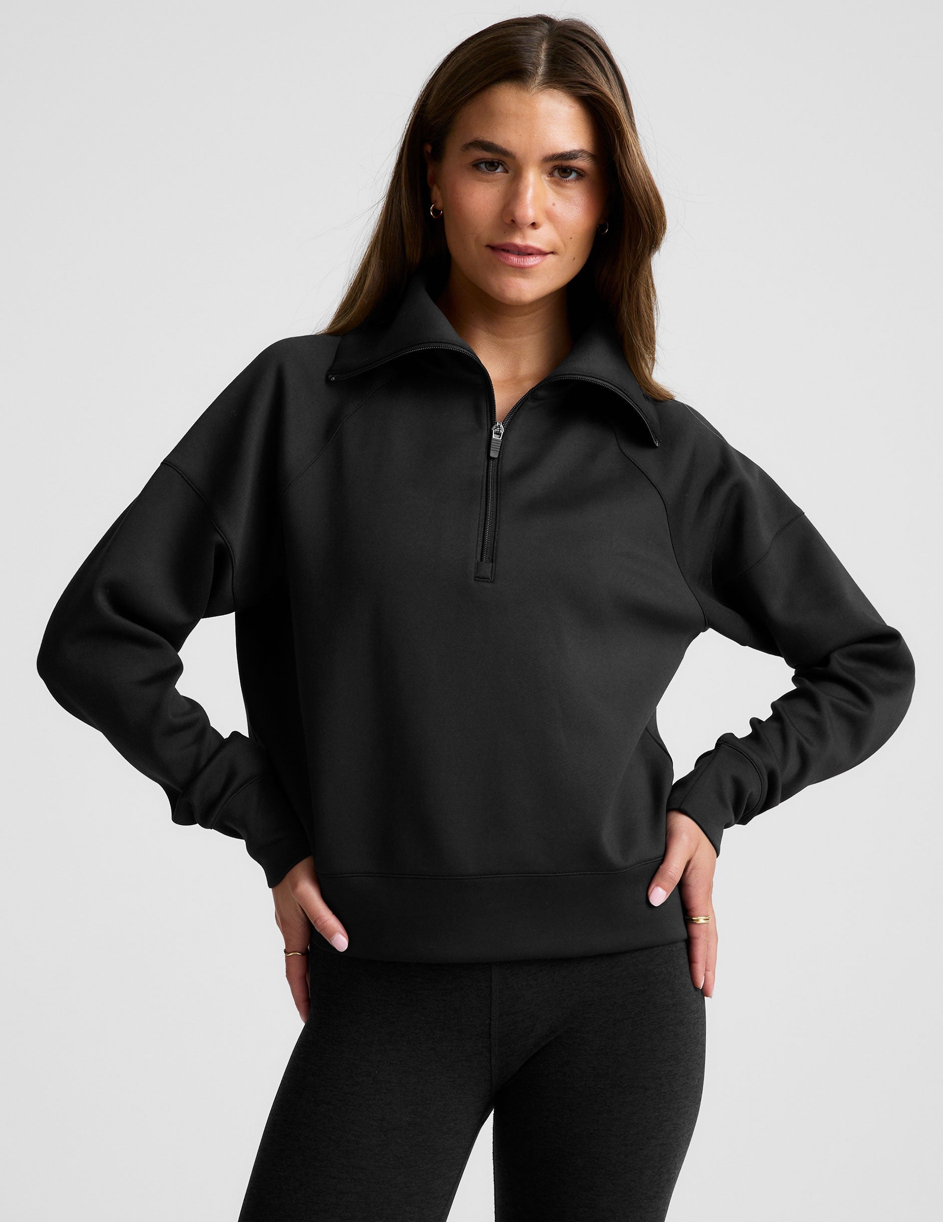 model wearing a black long length quarter zip pullover against a plain background.