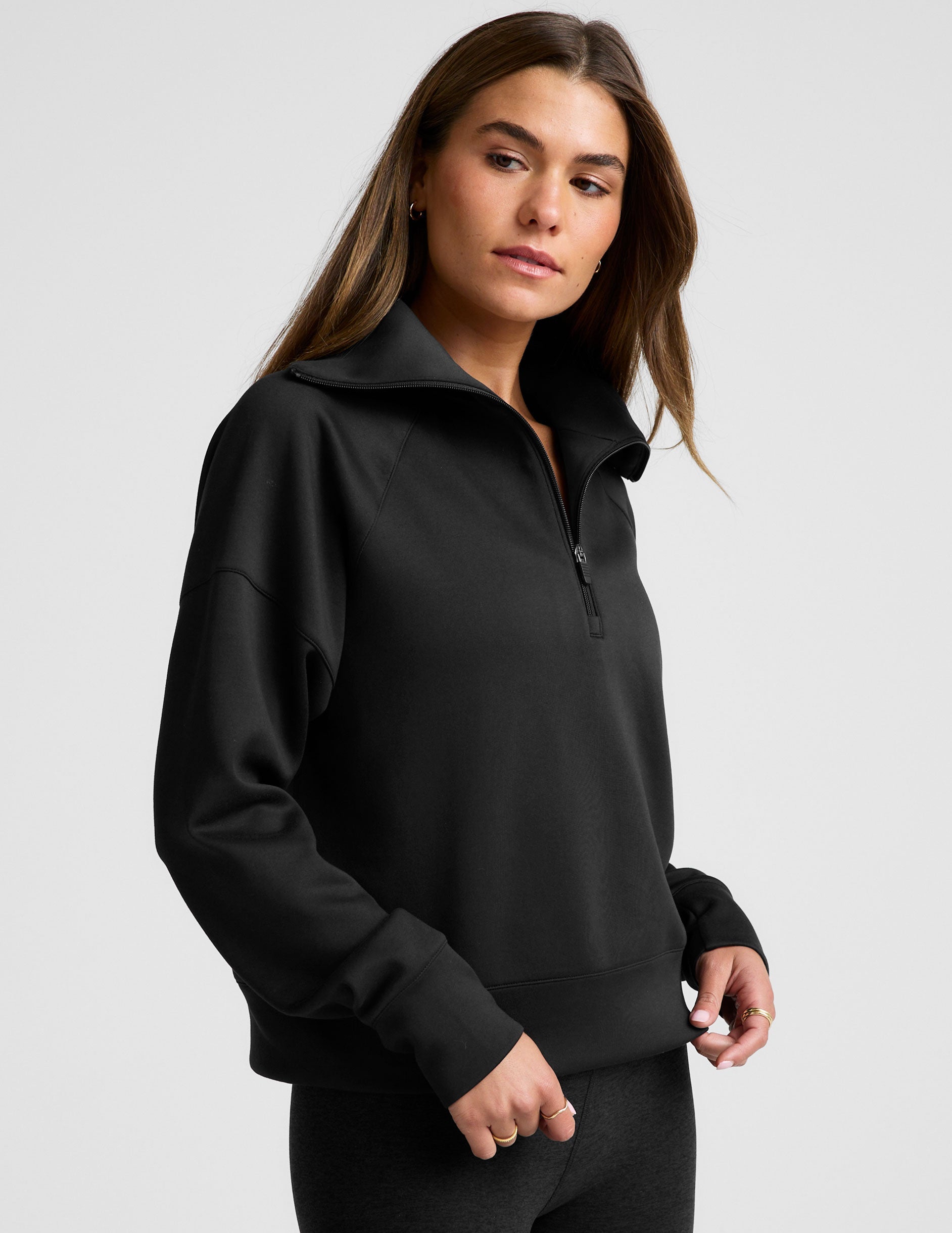 model wearing a black long length quarter zip pullover against a plain background.