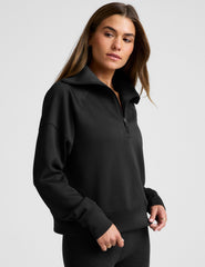model wearing a black long length quarter zip pullover against a plain background.