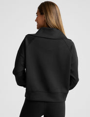 model wearing a black long length quarter zip pullover against a plain background.