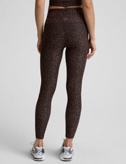 person wearing brown leopard print leggings on a plain background.