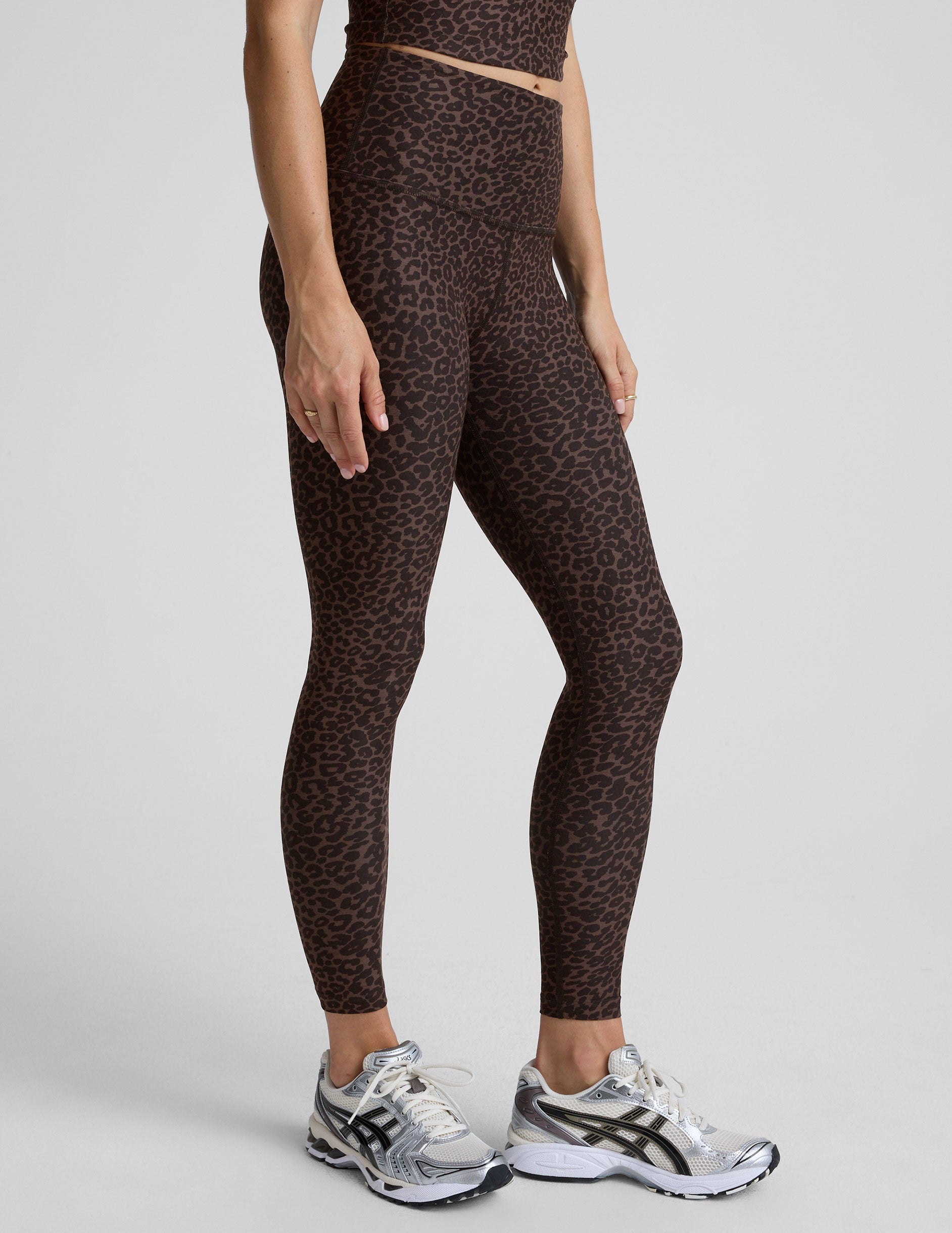 person wearing brown leopard print leggings on a plain background.