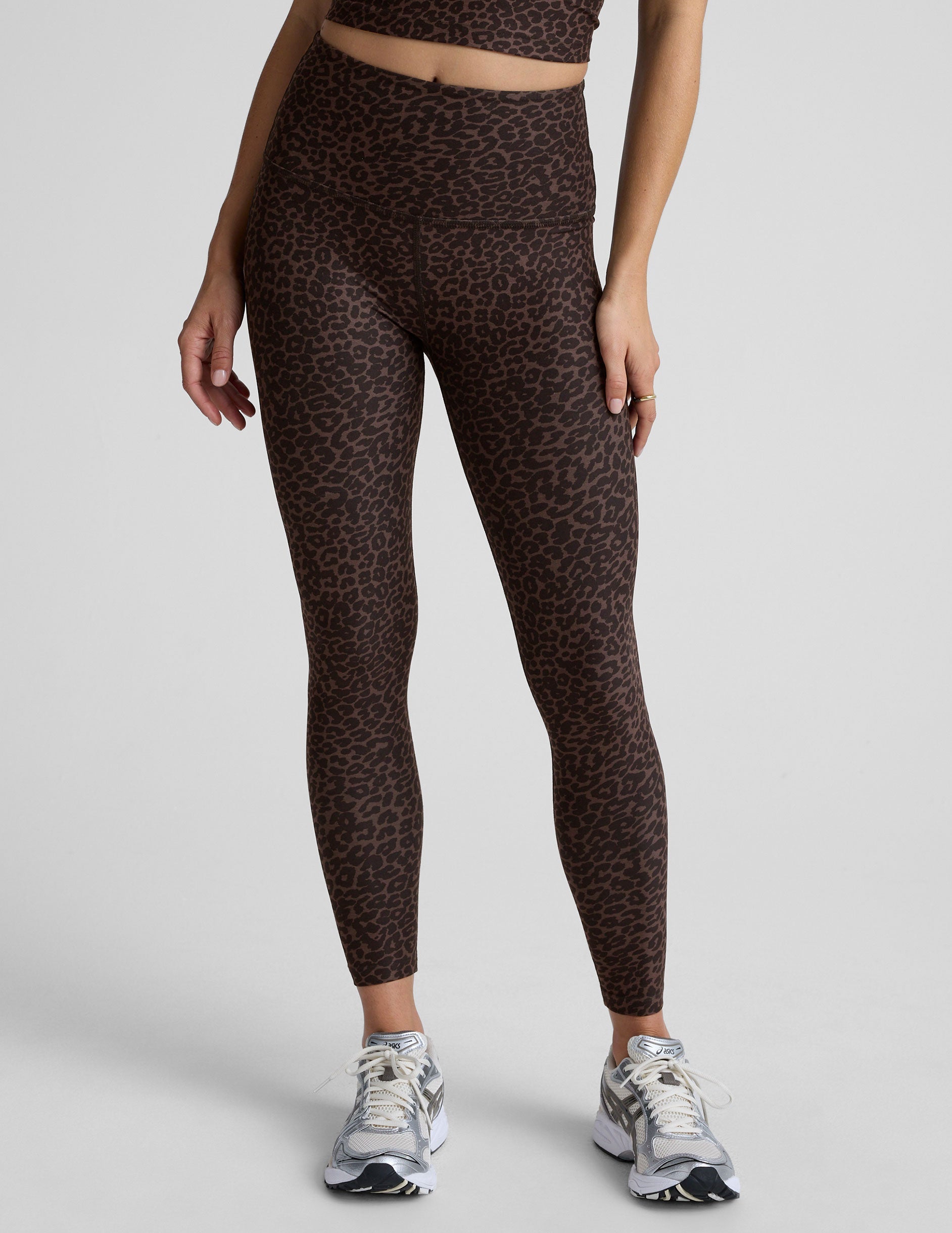 person wearing brown leopard print leggings on a plain background.