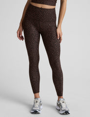 person wearing brown leopard print leggings on a plain background.