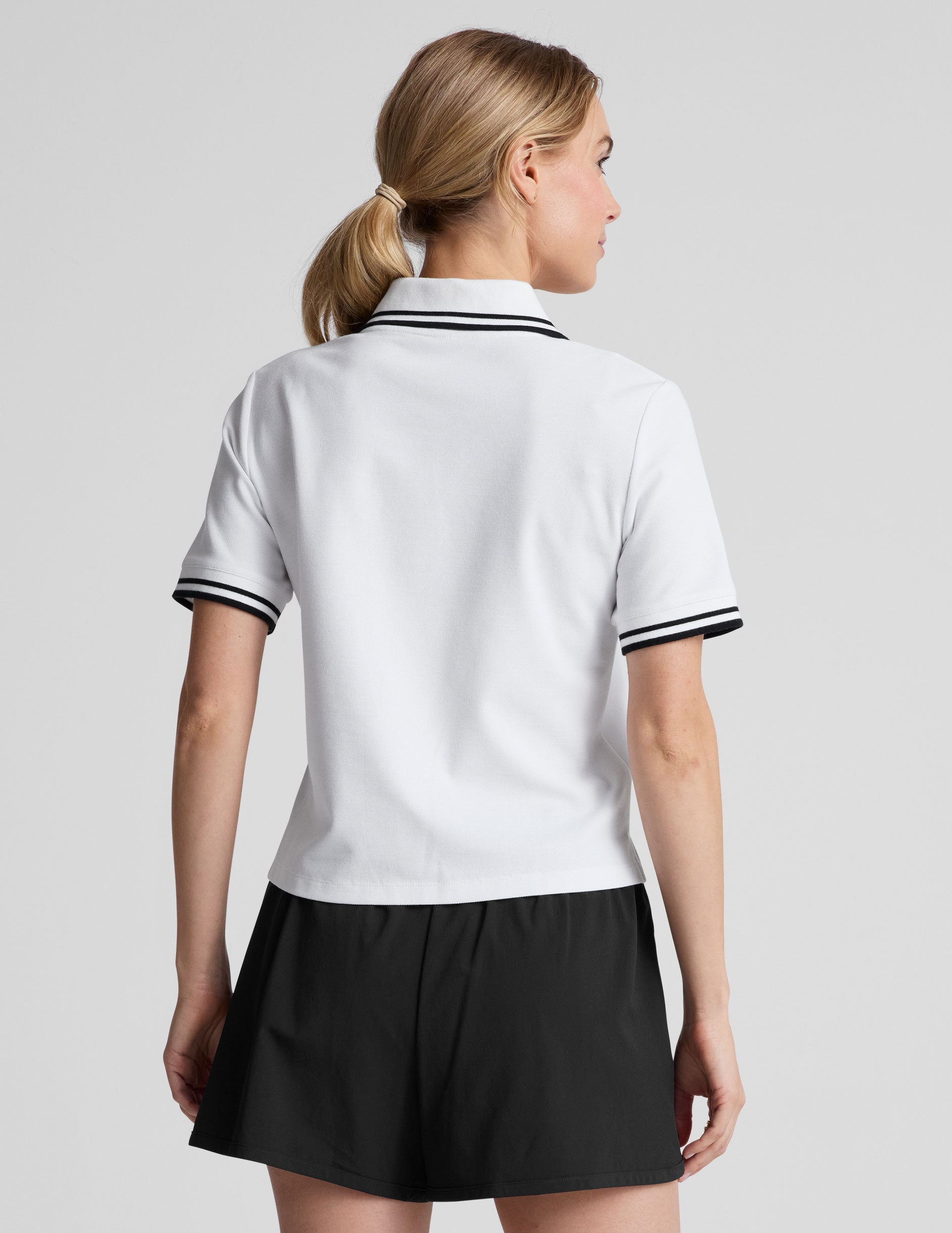 white fitted polo style short sleeve t-shirt with a stripe rib collar and cuff, front placket with buttons, and side slits. 