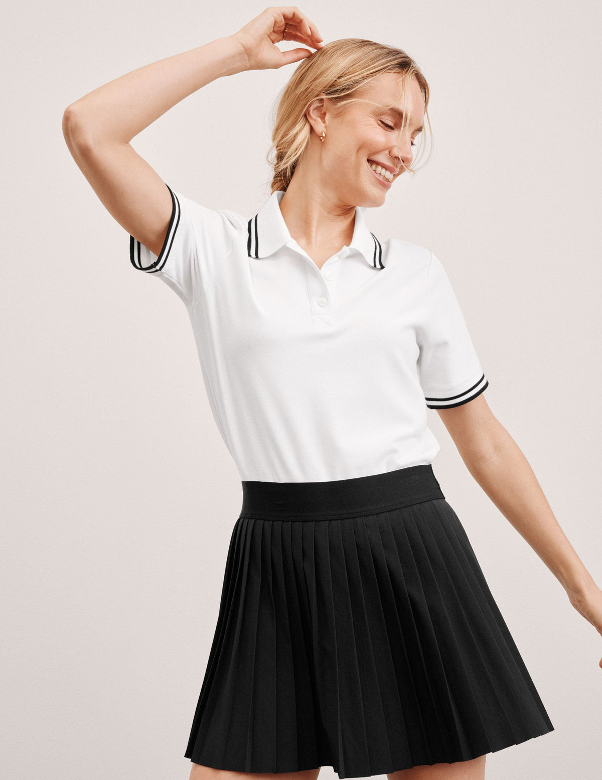 white fitted polo style short sleeve t-shirt with a stripe rib collar and cuff, front placket with buttons, and side slits. 