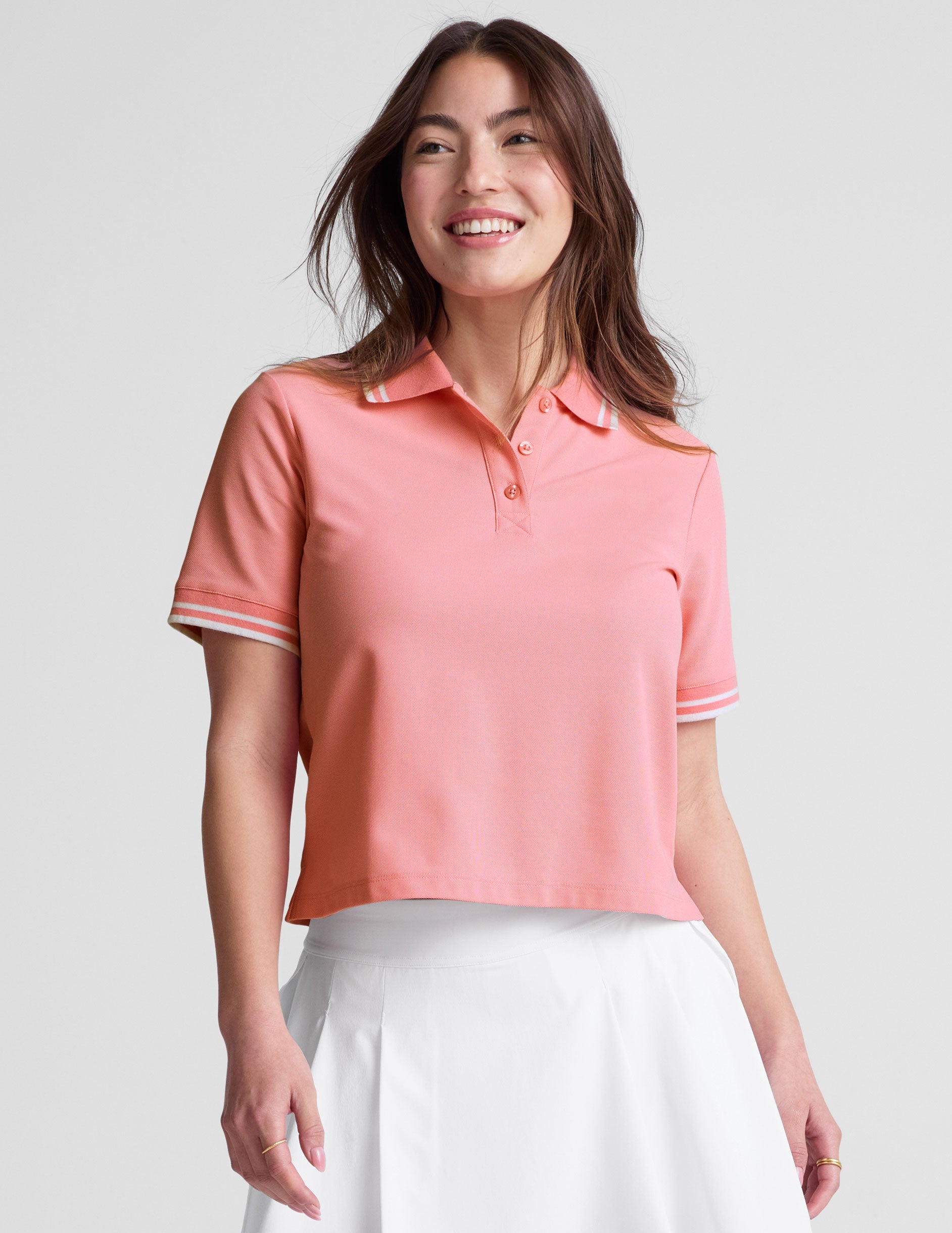 pink polo style top with a stripe rib collar and cuff , front placket with buttons, side slits, and hits at a high hip length. 