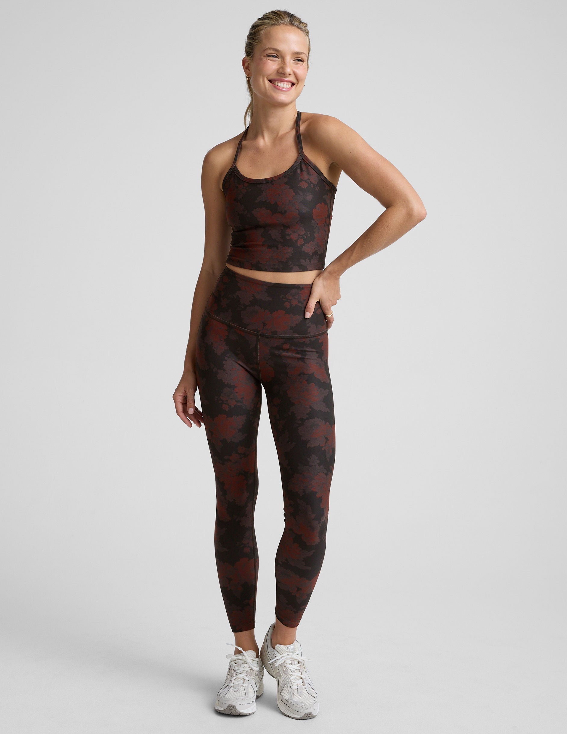 person wearing red and brown printed leggings on a light gray background.