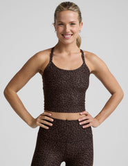 woman wearing a brown leopard print cropped tank and leggings on a gray background.