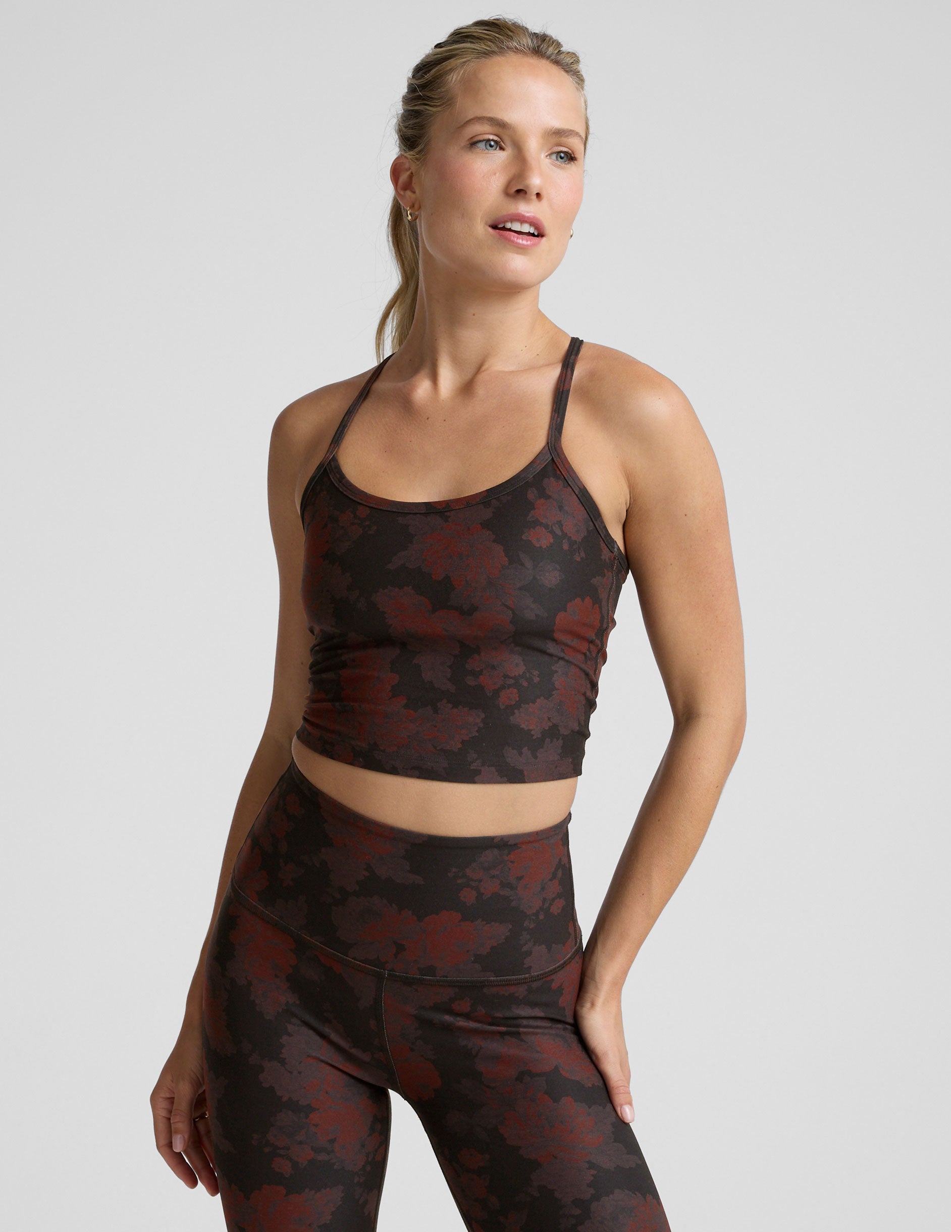 woman wearing a red and brown printed cropped tanks and leggings.