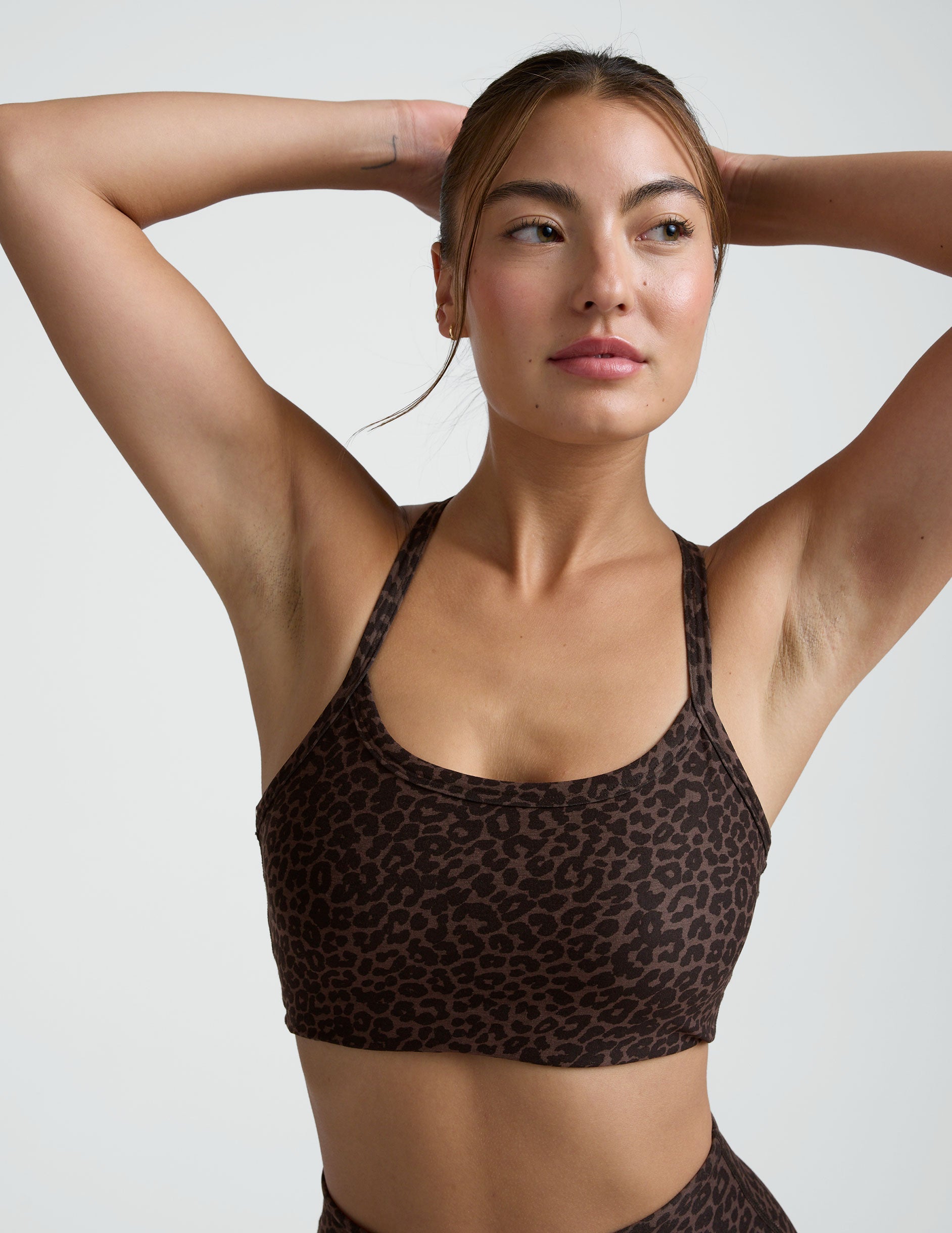 Woman wearing a brown leopard printed  bra and leggings on a plain background.