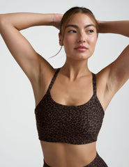 Woman wearing a brown leopard printed  bra and leggings on a plain background.
