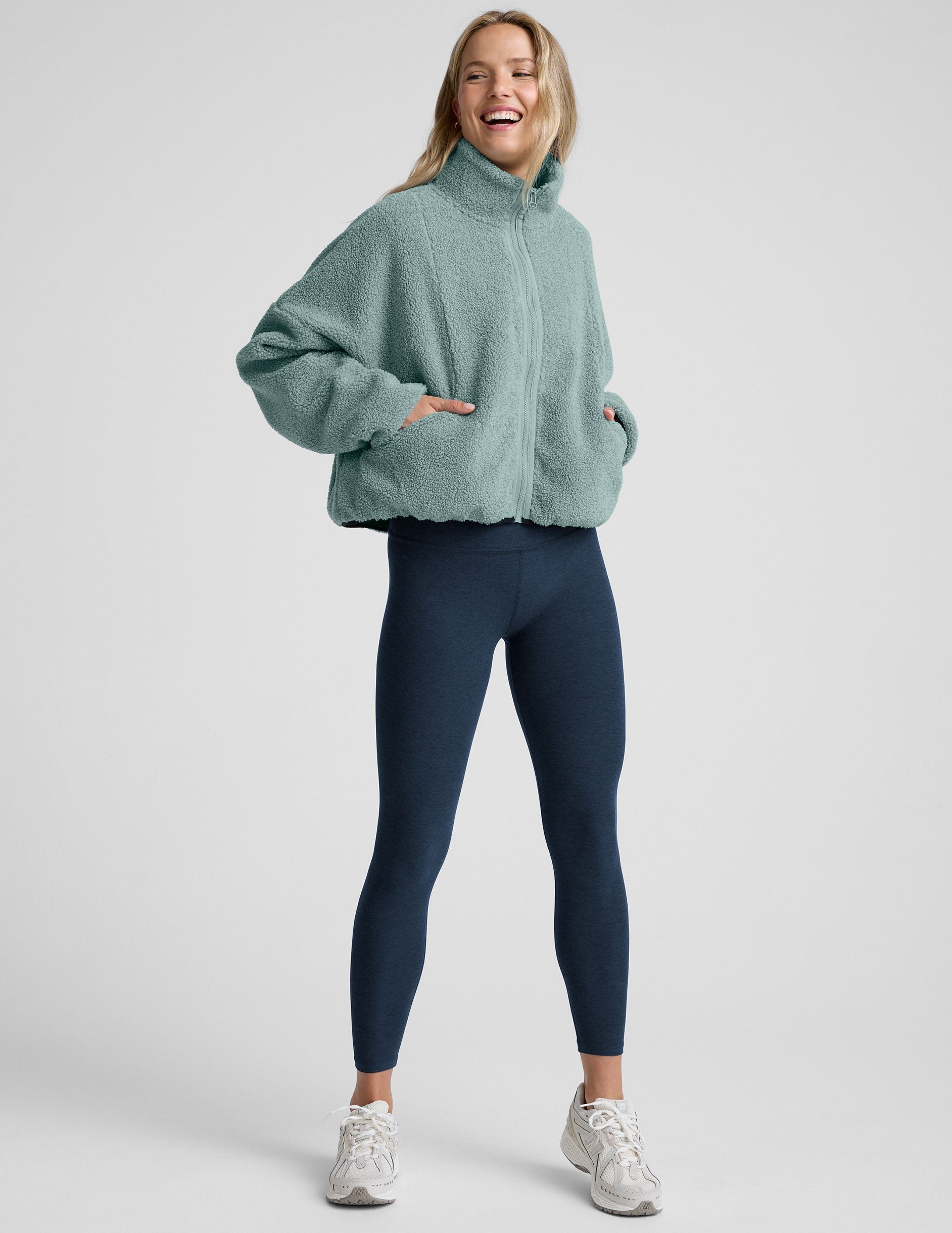 model wearing a blue zip-up fleece jacket against a plain background.