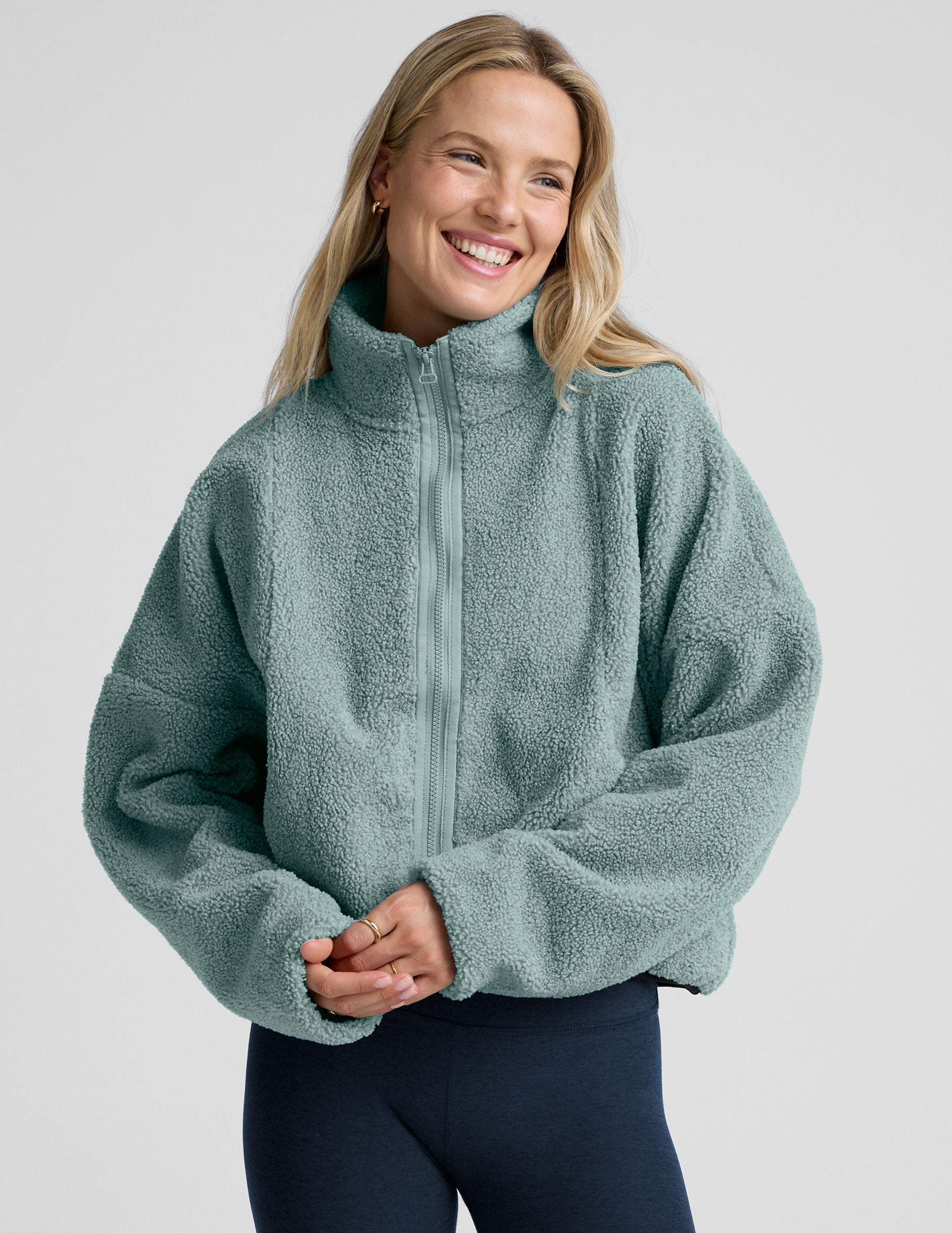 model wearing a blue zip-up fleece jacket against a plain background.