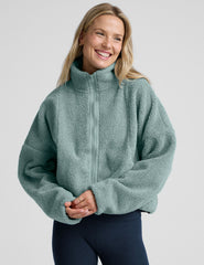 model wearing a blue zip-up fleece jacket against a plain background.
