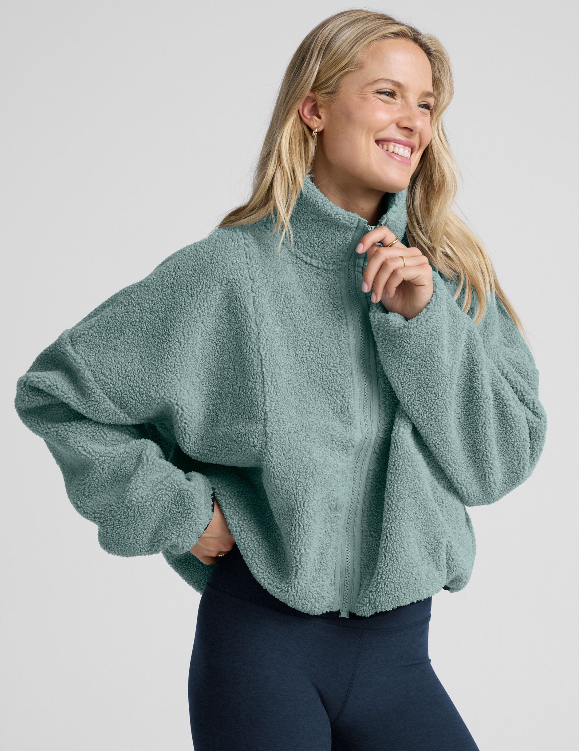 model wearing a blue zip-up fleece jacket against a plain background.