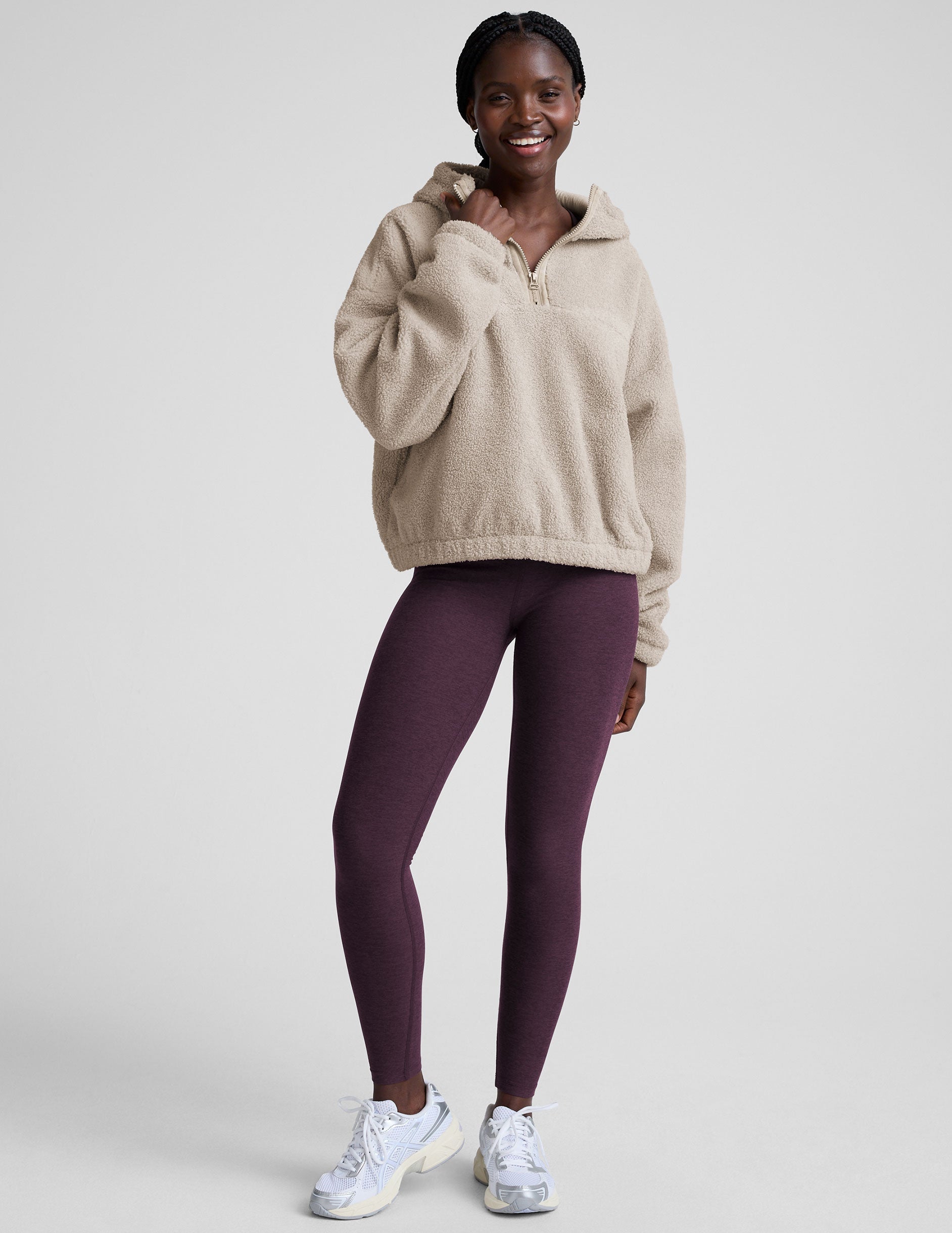 model wearing a beige fleece quarter zip pullover with a plain background.