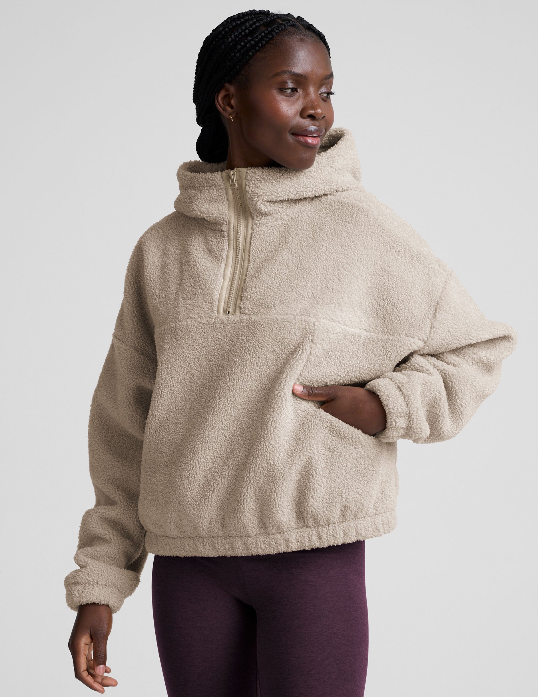 model wearing a beige fleece quarter zip pullover with a plain background.