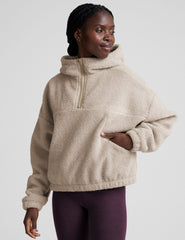 model wearing a beige fleece quarter zip pullover with a plain background.