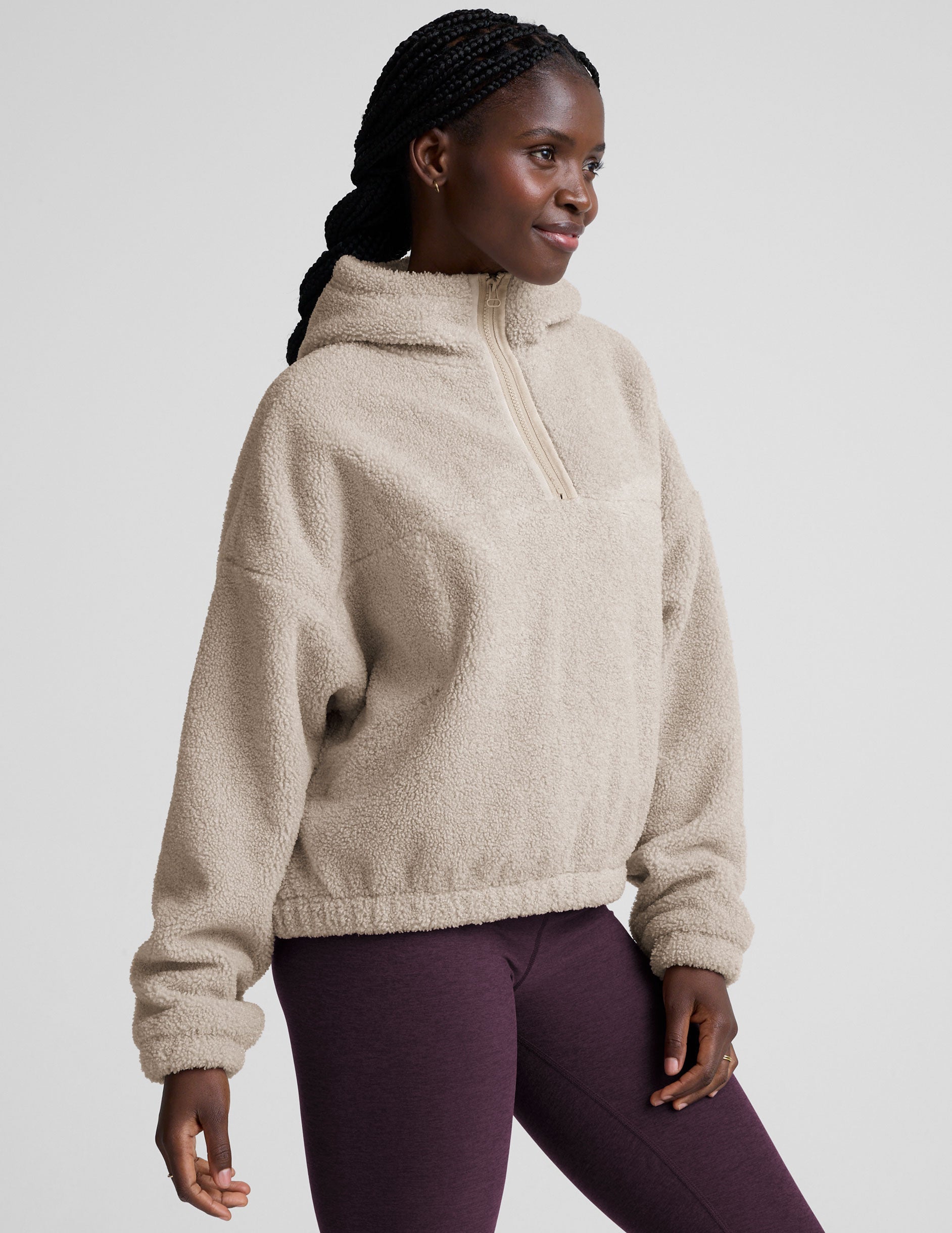 model wearing a beige fleece quarter zip pullover with a plain background.