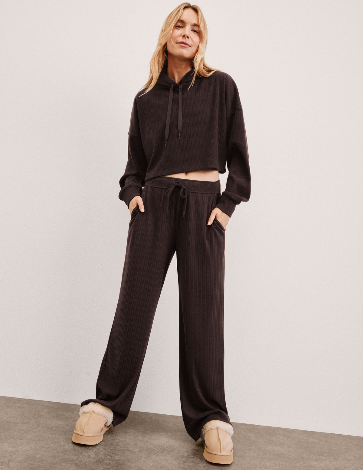 model wearing brown ribbed wide leg pants with a drawcord at waistband against a plain background.