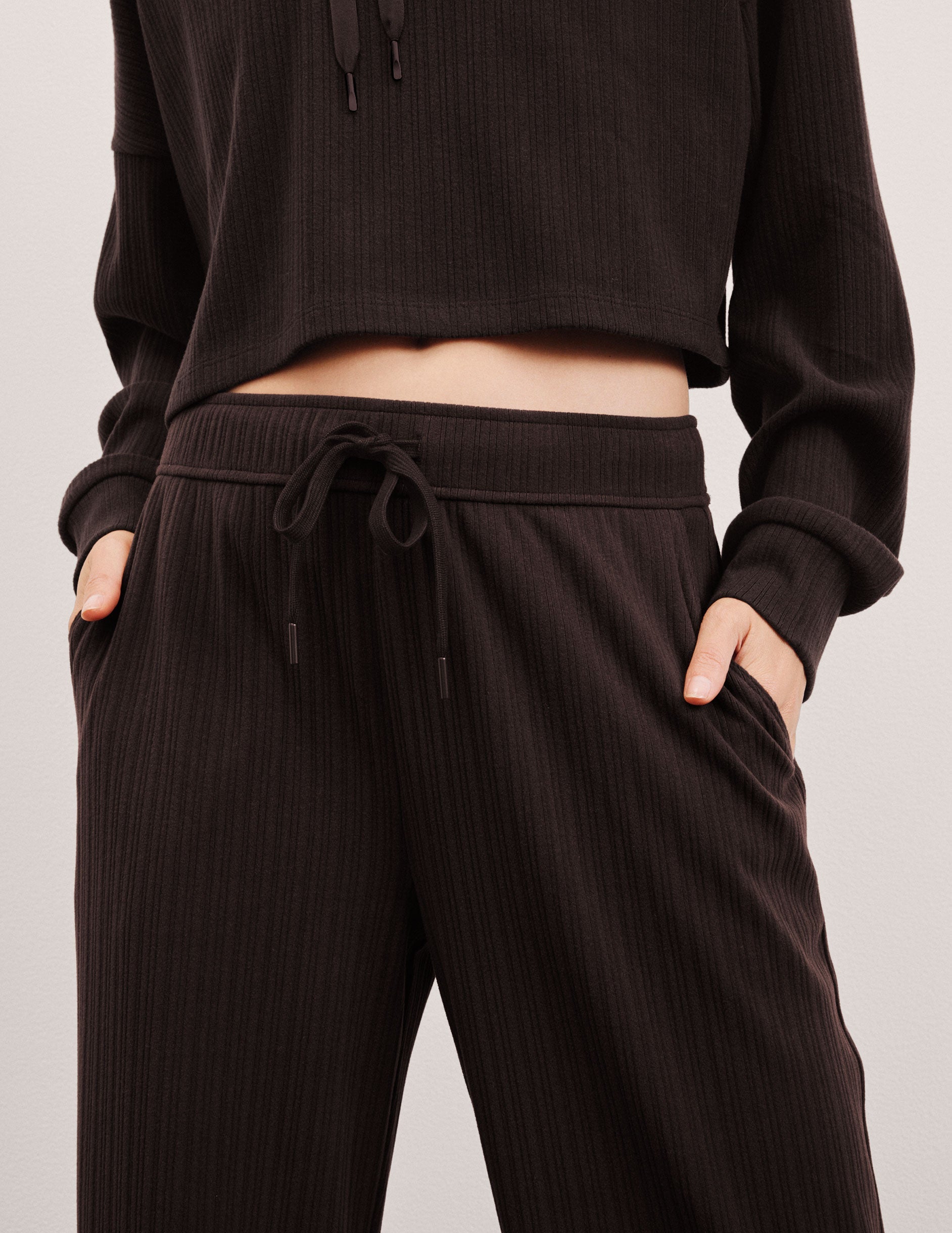 model wearing brown ribbed wide leg pants with a drawcord at waistband against a plain background.