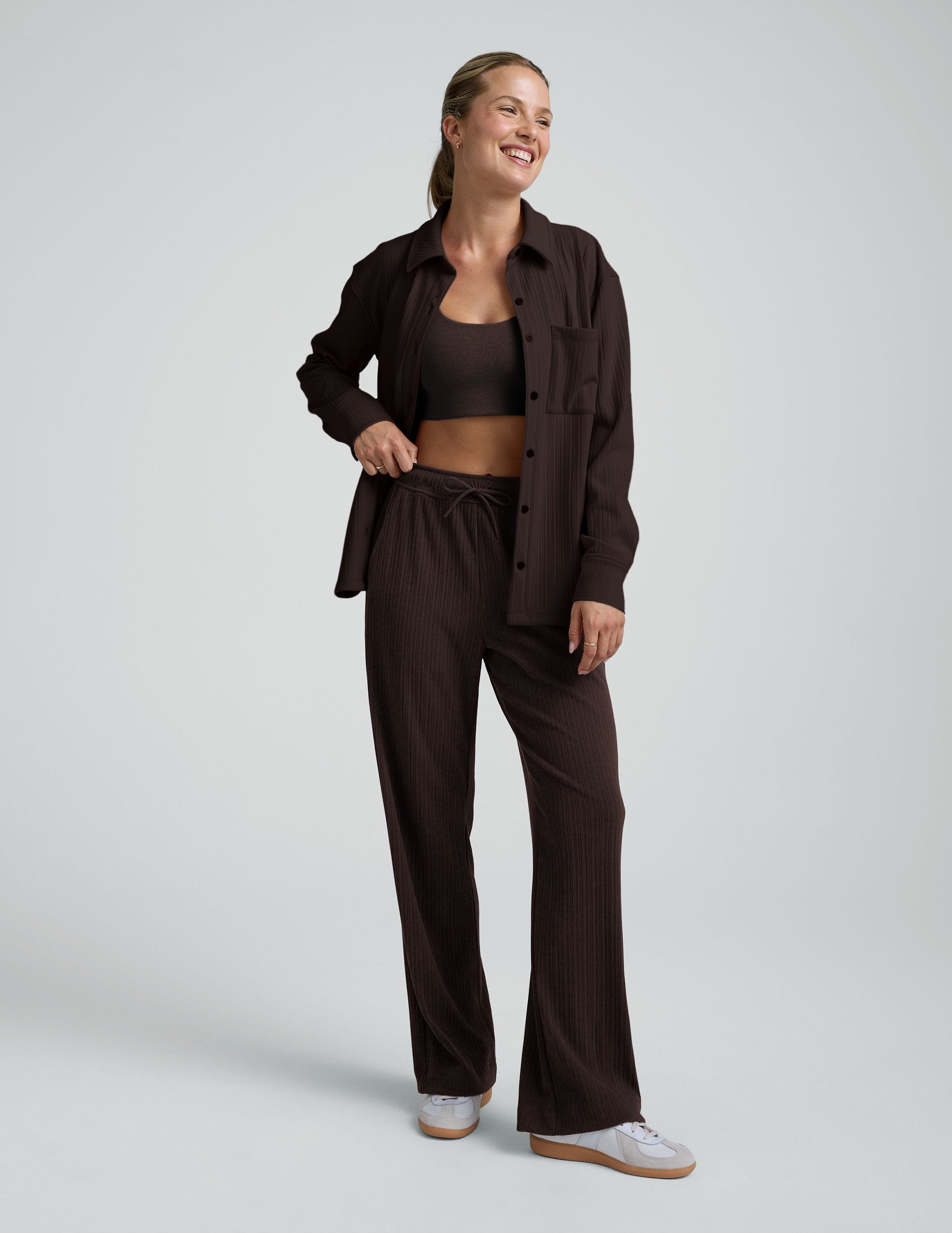 model wearing brown ribbed wide leg pants with a drawcord at waistband against a plain background.