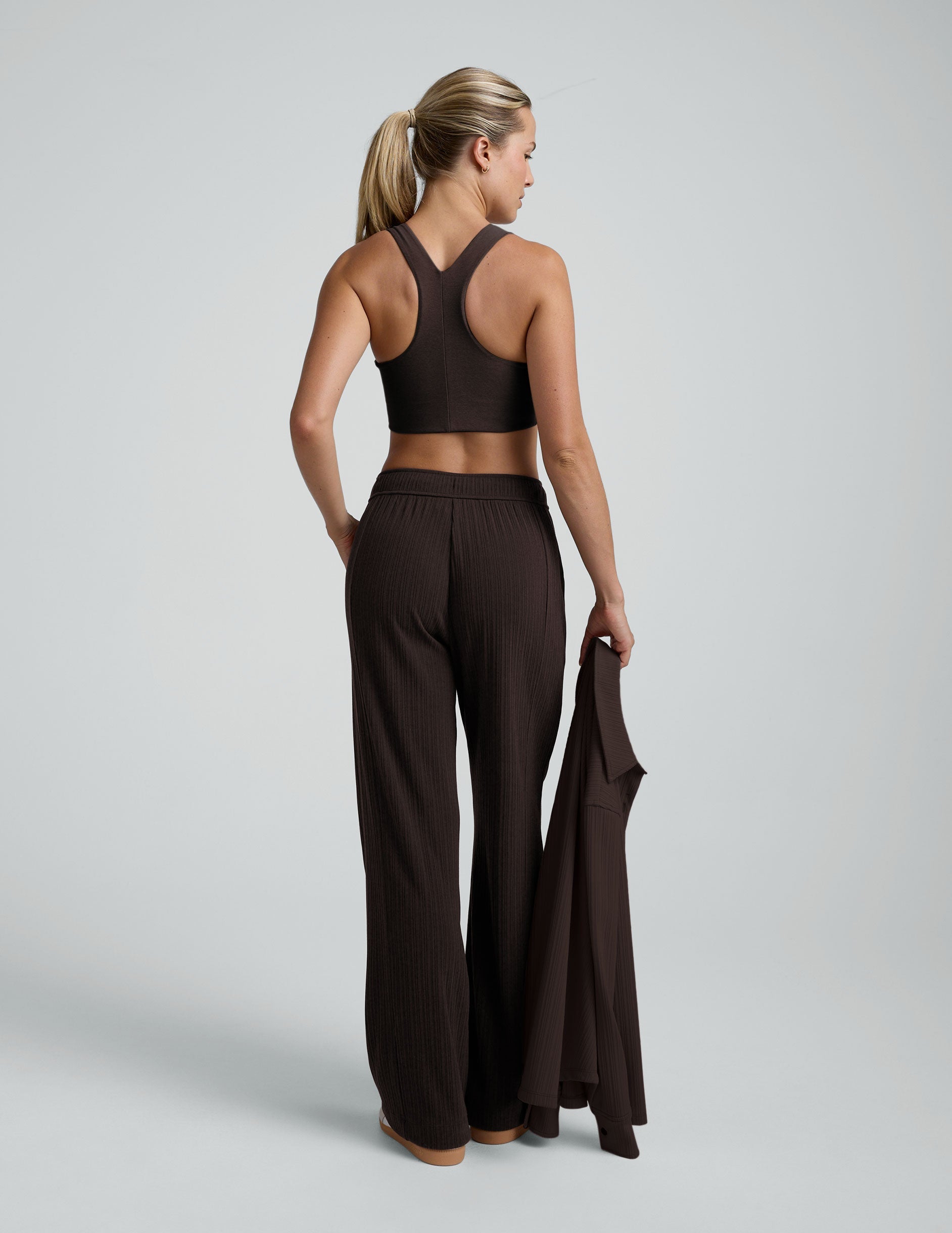 model wearing brown ribbed wide leg pants with a drawcord at waistband against a plain background.