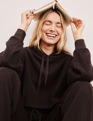 model wearing a brown ribbed cropped hoodie against a plain background.