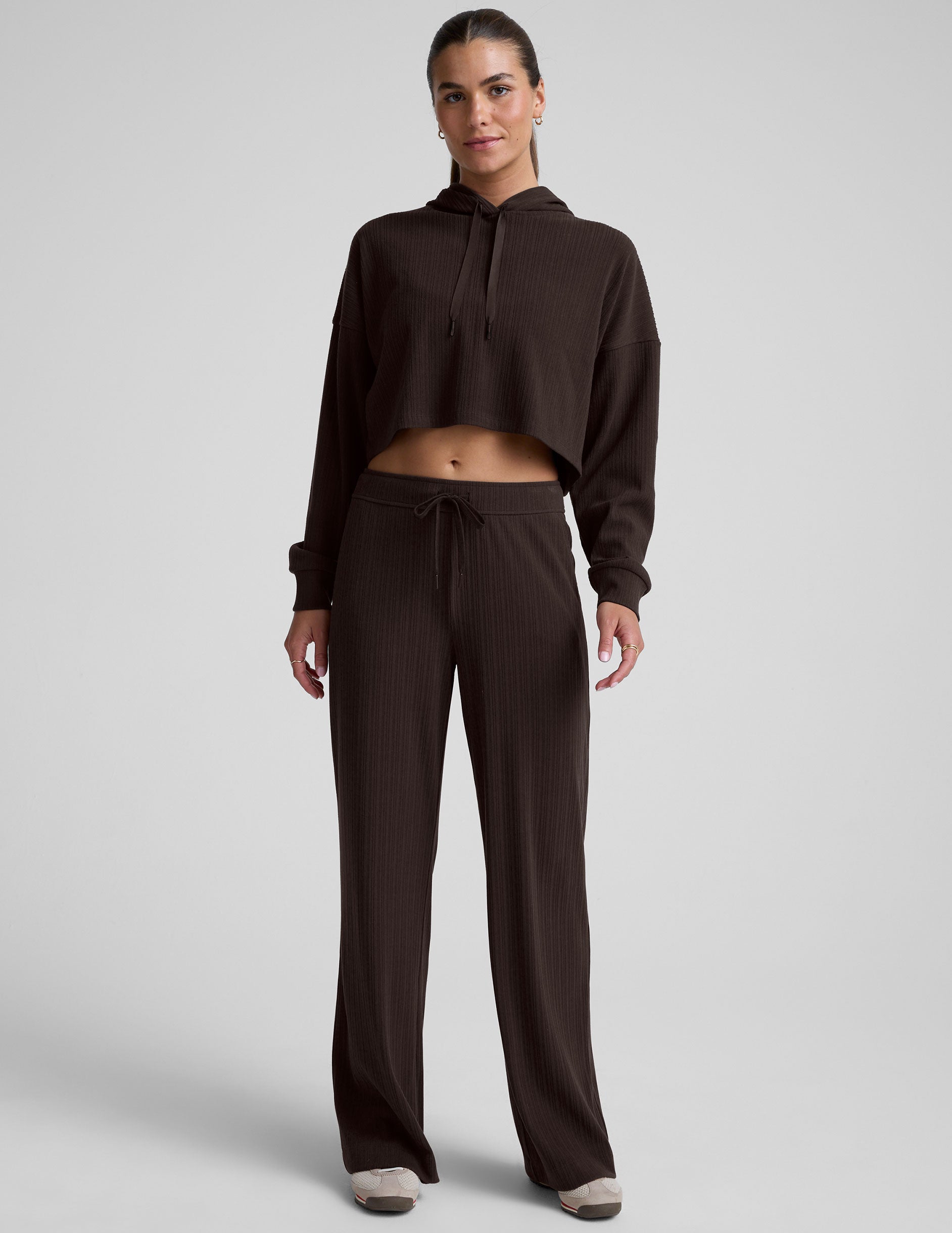 model wearing a brown ribbed cropped hoodie against a plain background.
