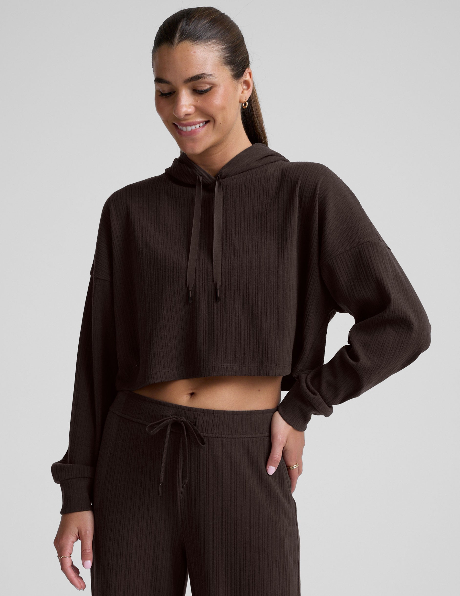 model wearing a brown ribbed cropped hoodie against a plain background.