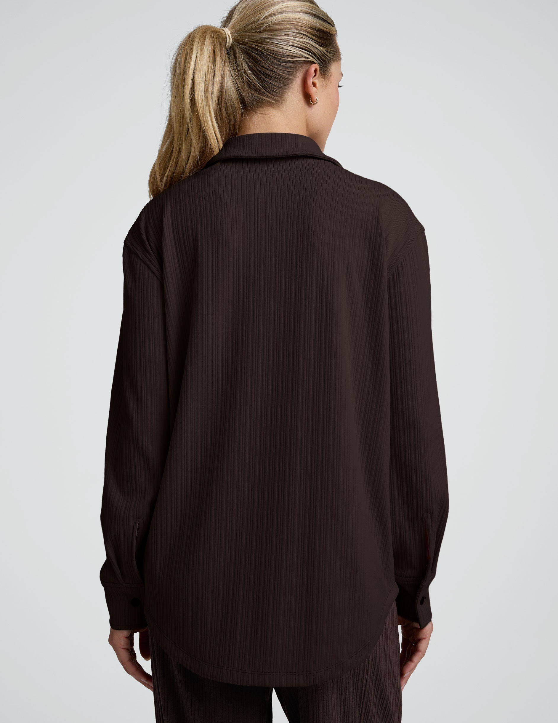 model wearing a brown ribbed button down top and brown ribbed pants against a plain background.