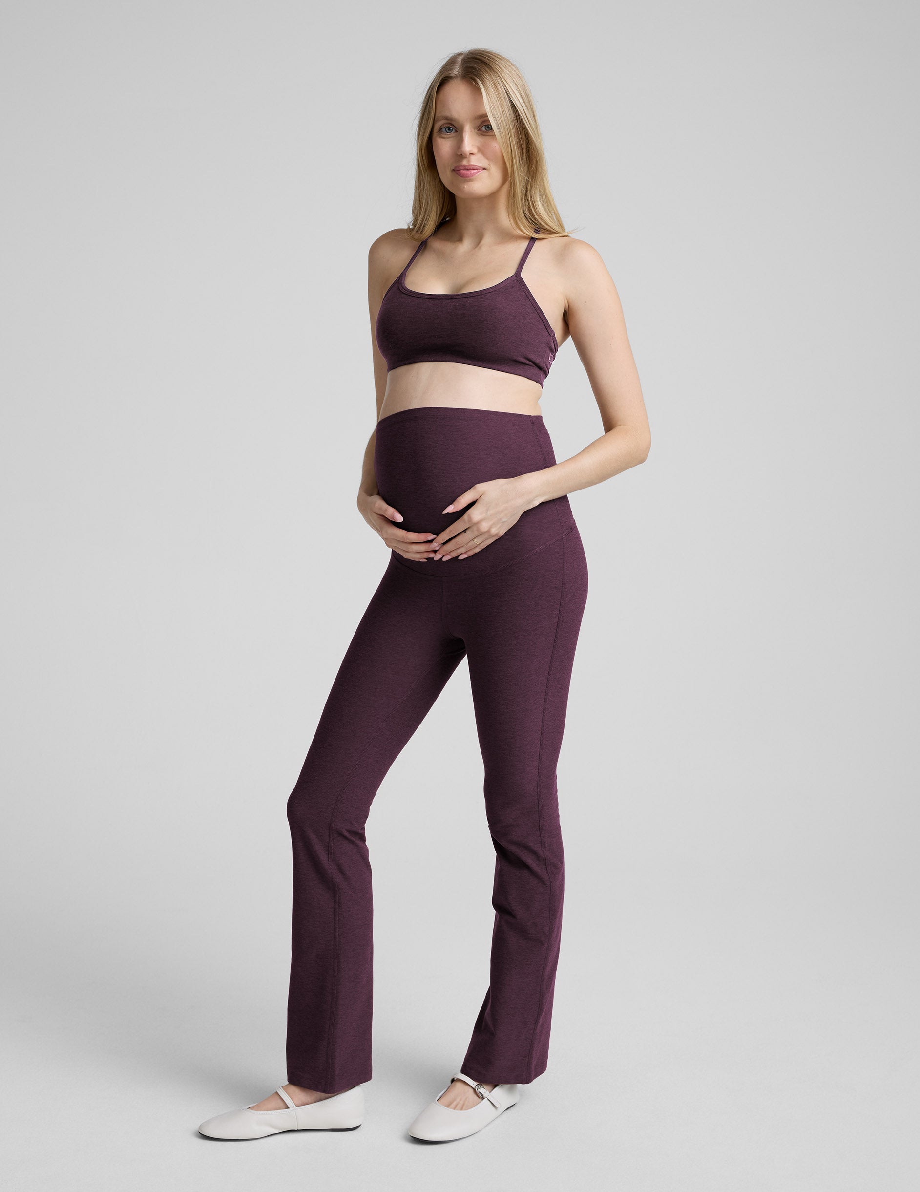 person wearing purple maternity bootcut style pants against a plain background.