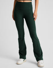 model wearing green high-waisted bootcut pants on a light gray background.