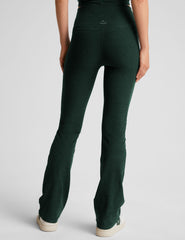 model wearing green high-waisted bootcut pants on a light gray background.